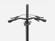 Close-up of a bicycle handlebar with black grips, brake levers, and a black stem against a light gray background.