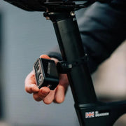 Lifestyle image of a hand easily attaching the Magicshine Seemee 300 taillight to the back of a bicycle seatpost