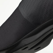 Close-up of a black slip-on shoe with textured surface and sole on a white background