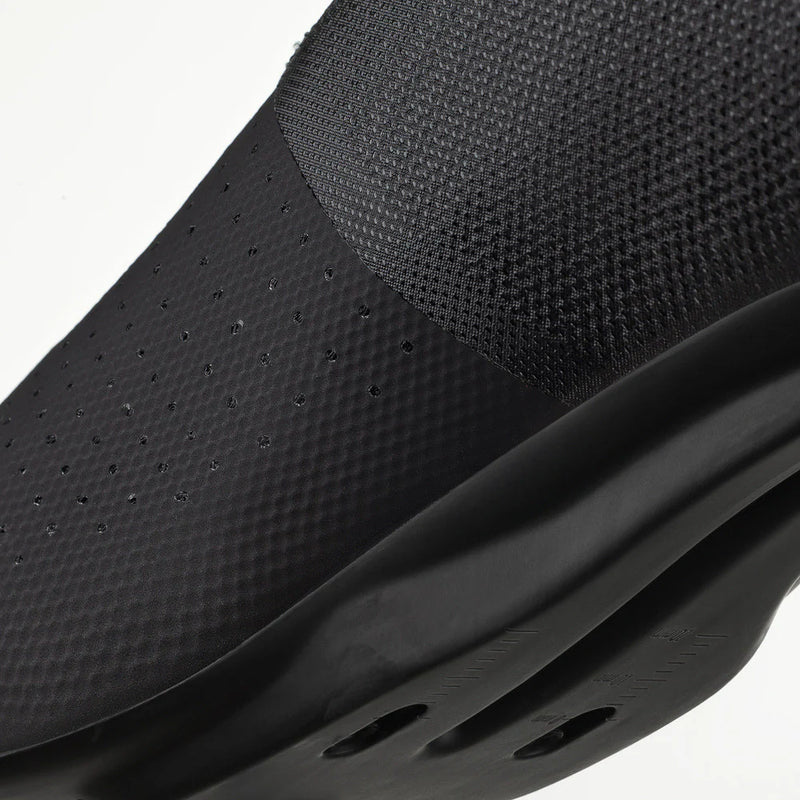 Close-up of a black slip-on shoe with textured surface and sole on a white background