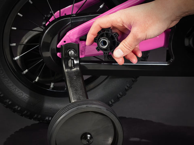 Close-up of a hand adjusting a wheel on a pink scooter.