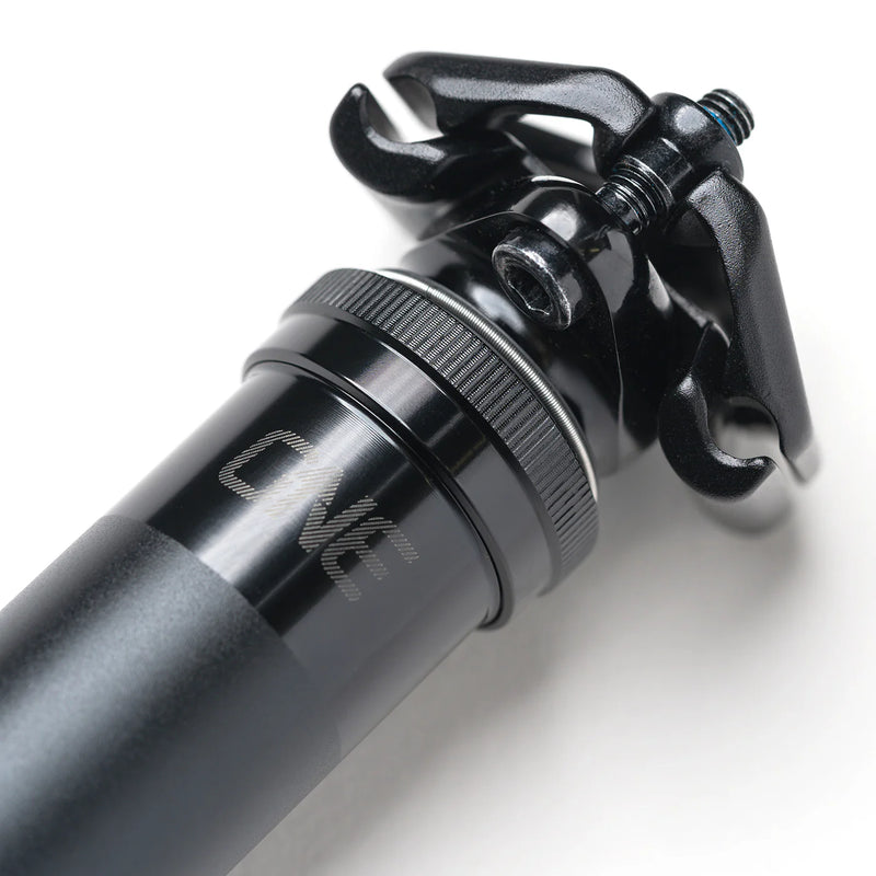 Close-up of a black bicycle shock absorber with 'ONE' branding on a white background
