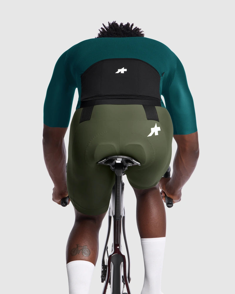 Person wearing green cycling outfit with visible brand logo on a white background