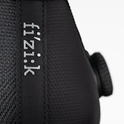 Close-up of a black cycling helmet with 'fi'zi:k' branding on a white background