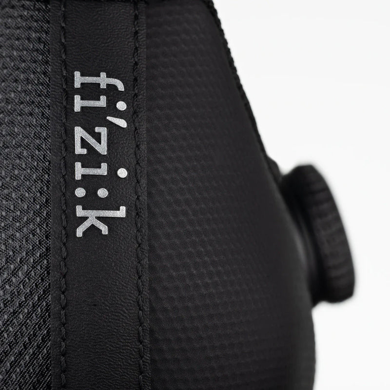 Close-up of a black cycling helmet with 'fi'zi:k' branding on a white background