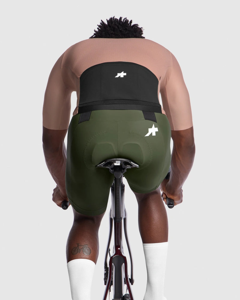 Person wearing green cycling shorts with a visible brand logo on a white background