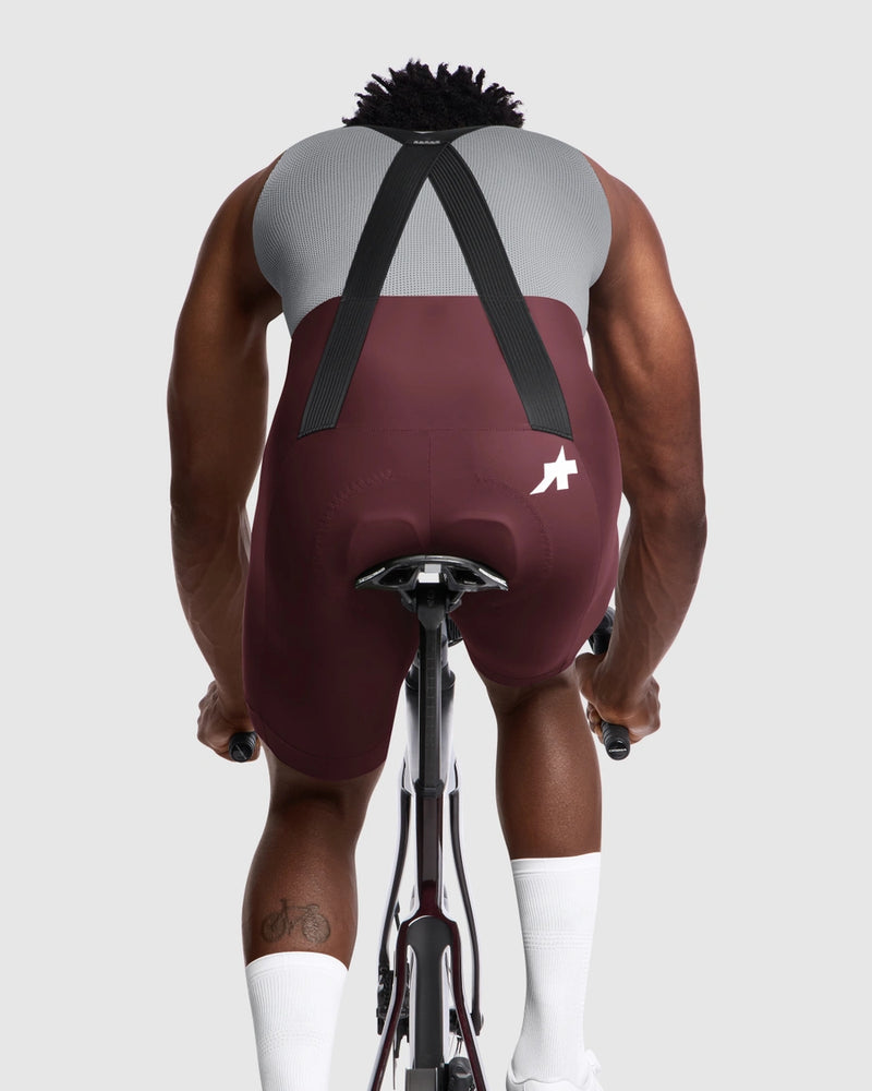 Person wearing a maroon and gray cycling outfit on a white background