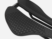 Close-up of a black bicycle saddle with textured surface on a white background