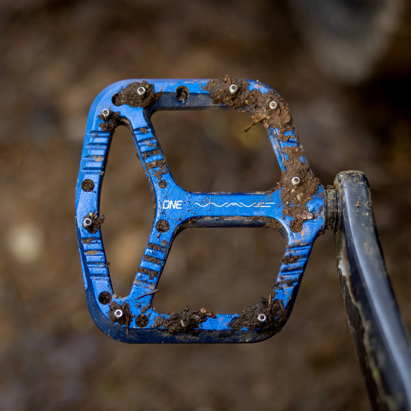 Blue bicycle pedal with 'ONE' branding on a blurred background