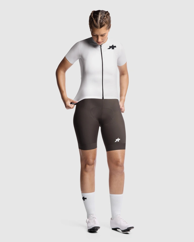 Person wearing a white cycling jersey and black shorts on a white background