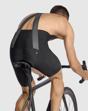 Person riding a bicycle wearing black cycling shorts on a light gray background