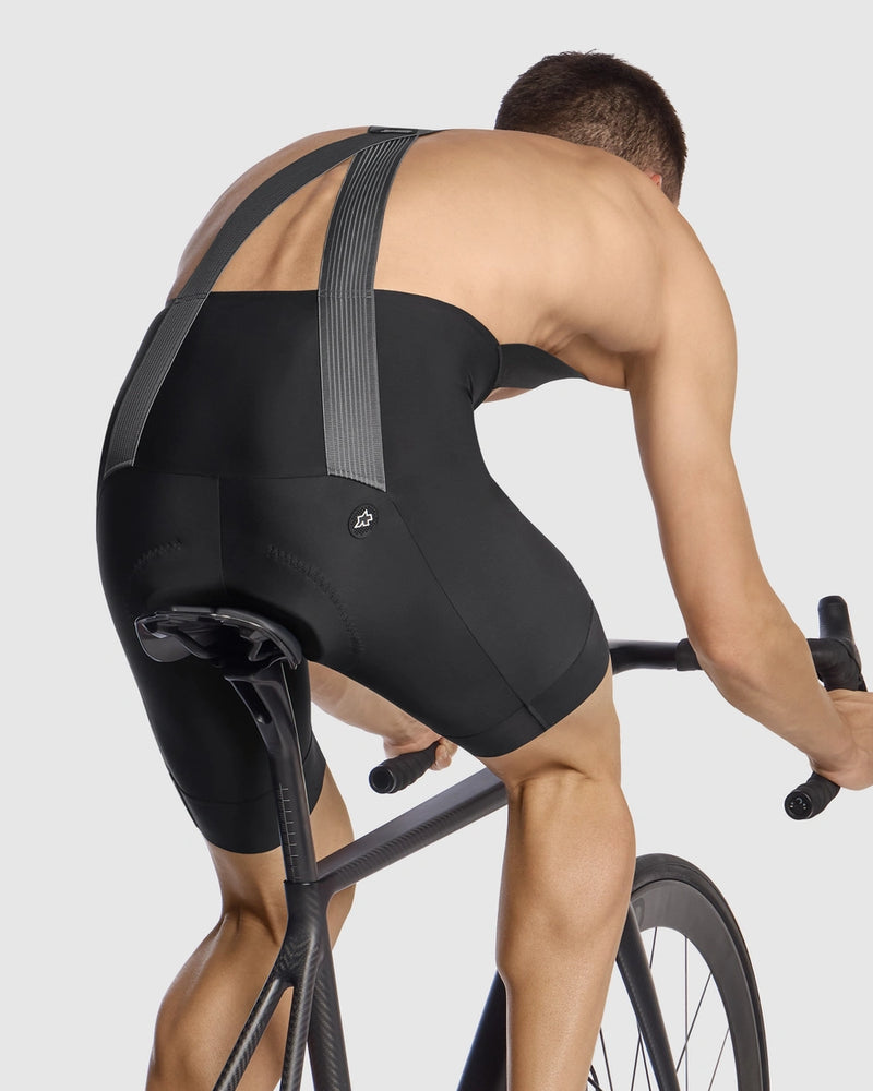 Person riding a bicycle wearing black cycling shorts on a light gray background