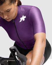 Person wearing a purple cycling outfit with a logo on a white background