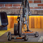 lifstyle shot of four JetBlack Freedom Rocker Feet being used on a bicycle trainer in an indoor setup, mat and fan also included in image