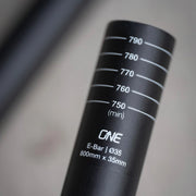 Close-up of a black bicycle handlebar with measurement markings and 'ONE' branding.