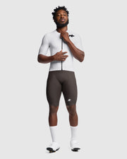 Person wearing a white cycling jersey and black shorts on a white background