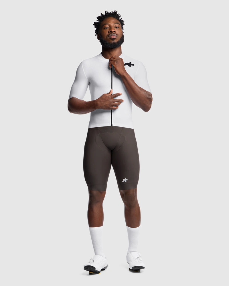 Person wearing a white cycling jersey and black shorts on a white background