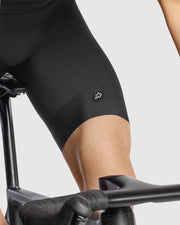 Person wearing black cycling shorts on a bike with a plain background