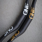 Close-up of black bicycle handlebars with 'ONE' branding on a gray background