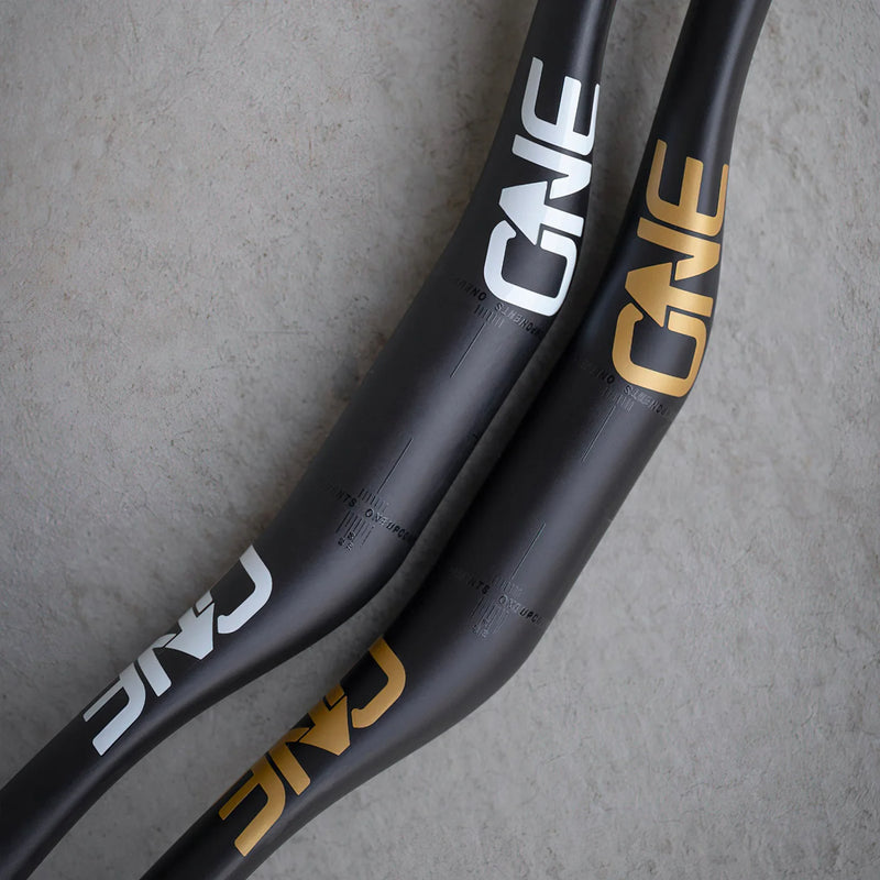 Close-up of black bicycle handlebars with 'ONE' branding on a gray background
