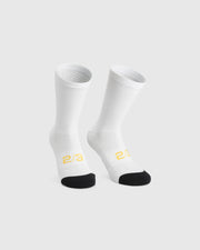 Assos Spring Fall Socks P3 cycling socks in White Series colourway, front view showing breathable knit construction, black reinforced toe panel, 18 cm cuff height, and yellow 2/3 graphic detailing.