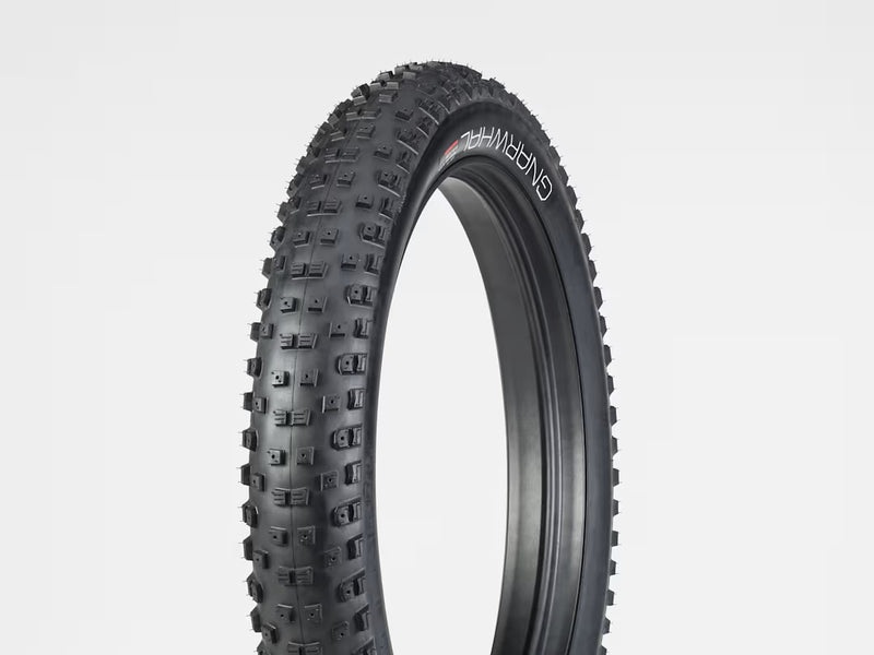 Black off-road tire with tread pattern on a light gray background