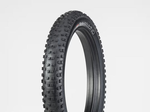 Black off-road tire with tread pattern on a light gray background