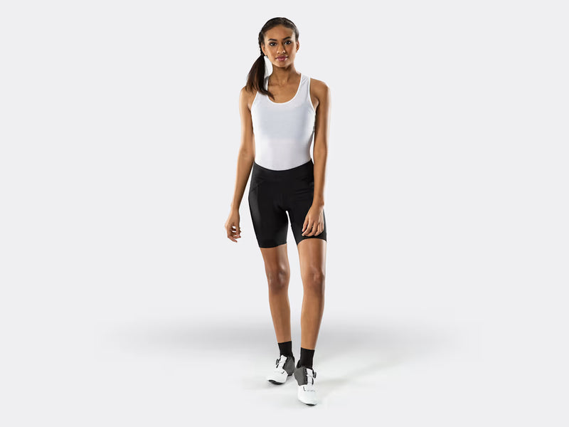 Full-body front view of a female model wearing the black Bontrager Meraj Women's Cycling Short with a fitted athletic tank, demonstrating the flattering compressive fit, wide waistband and performance-ready cycling ensemble.