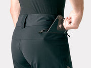 Bontrager OMW softshell pant in black worn, back view with phone slipping into a pocket
