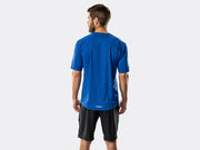 Rear studio view of male model wearing a blue t-shirt and black Bontrager Quantum fitness shorts, showing how the loose-fitting fabric and hem drape while riding or standing