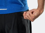 Close-up view of the upper rear hip of the black Bontrager Quantum shorts, showing the model interacting with the secure zippered back pocket