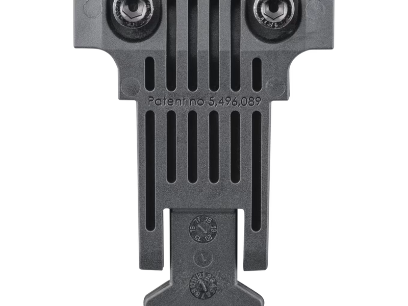 Close-up of the back of a dark gray metal firearm accessory or component with vertical slots, two circular elements at the top, and embossed patent text reading 'Patentino 5,496,089' on a white background.