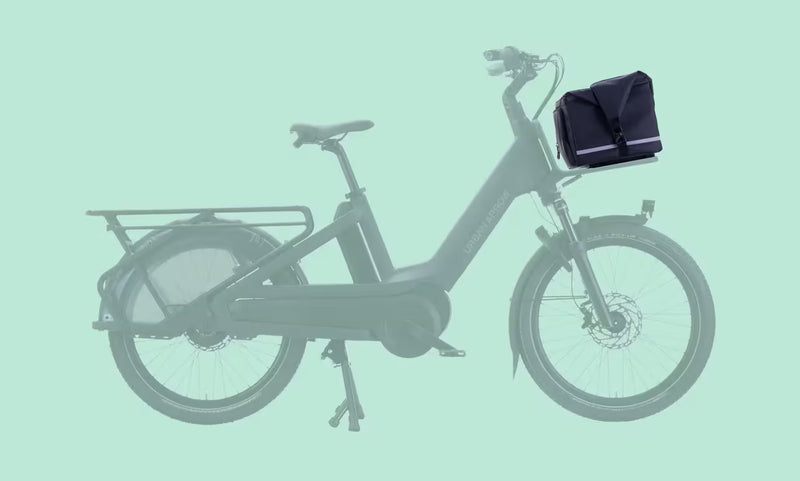 Urban Arrow Breeze Front Carrier Pannier MIK shown mounted on the front carrier of an Urban Arrow Breeze, with the bike displayed transparently against a solid turquoise background