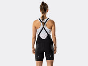 Bontrager Circuit women's black cycling bib shorts rear view on model, showcasing crossed elastic bib straps, Nature Breakaway design, signature red white and navy detail, reflective leg accents, and secure leg cuffs.