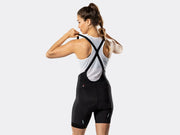 Bontrager Circuit women's black cycling bib shorts rear three-quarter view on model, highlighting the stretch bib straps, supportive fit, anatomical panel construction, and shape-retaining performance fabrics for road cycling.