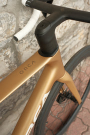 Orca M30ILTD PWR in Metallic Gold finish against a brick wall, closeup of ORCA