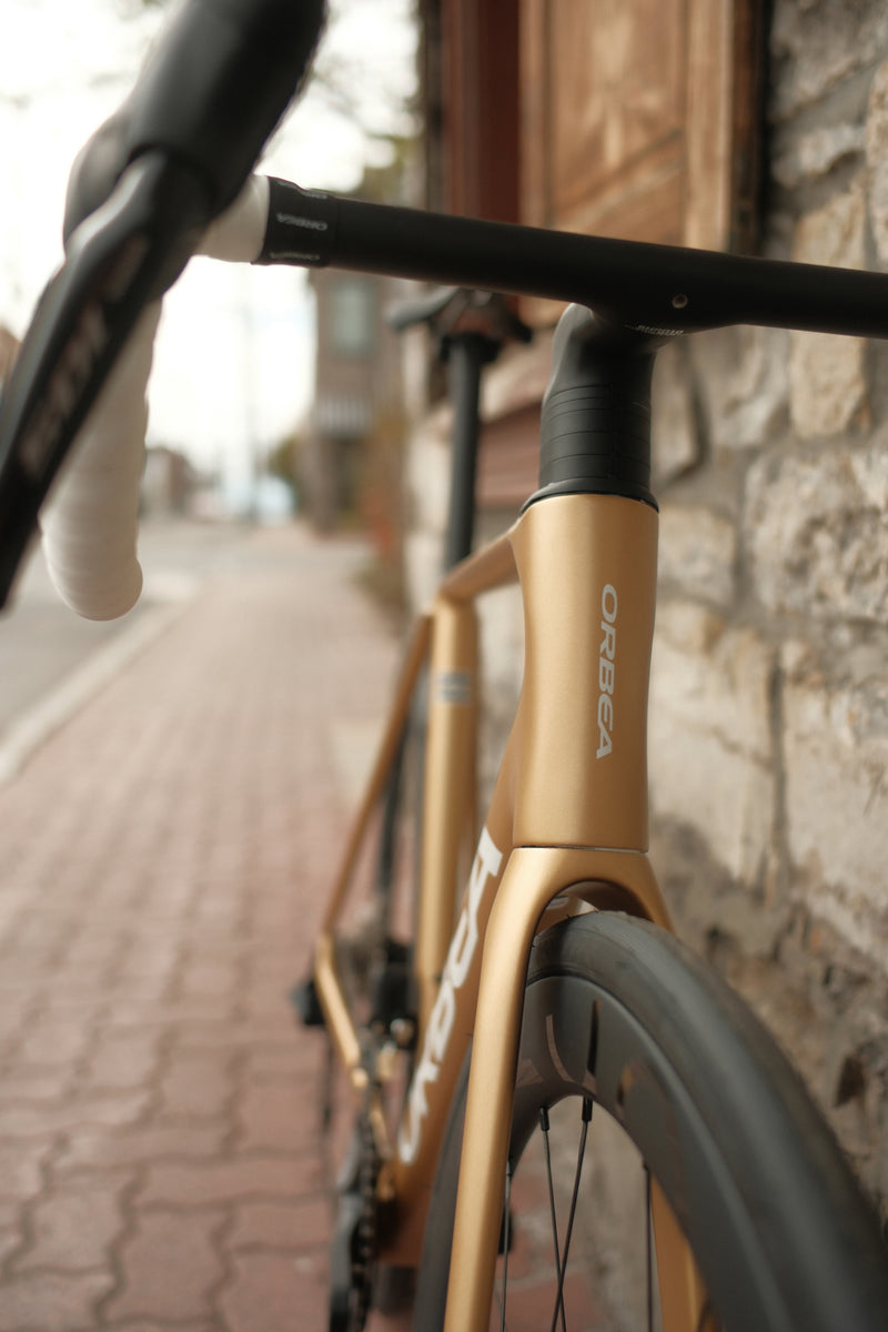 Orca M30ILTD PWR in Metallic Gold finish against a brick wall, front frame view