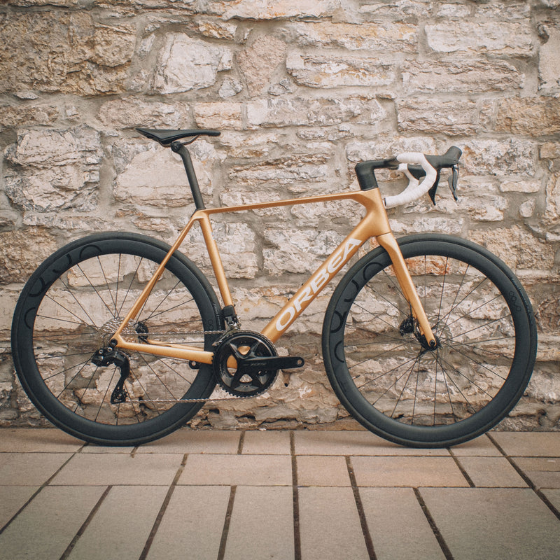 Orca M30ILTD PWR in Metallic Gold finish against a brick wall