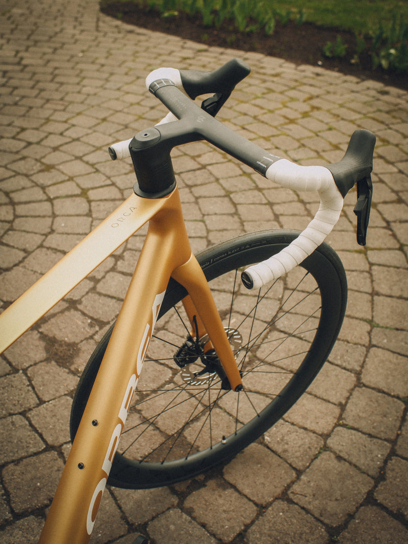 Orca M30ILTD PWR in Metallic Gold finish against a brick wall lifestyle image