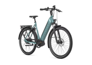 A low step electric bicycle in a muted teal color with black components, shown from a three-quarters front angle on a solid white background. The brand name 'GAZELLE' is printed vertically on the downtube.