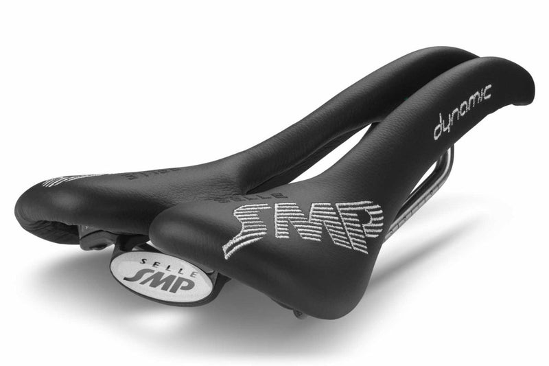 Selle SMP Dynamic Saddle in black with white stitched logos and raised rear section, shown at a back diagonal angle.