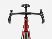 Front view of a red endurance road bicycle with black drop handlebars, black saddle, and black grips against a light gray background.
