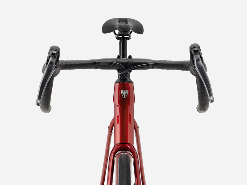 Front view of a red endurance road bicycle with black drop handlebars, black saddle, and black grips against a light gray background.
