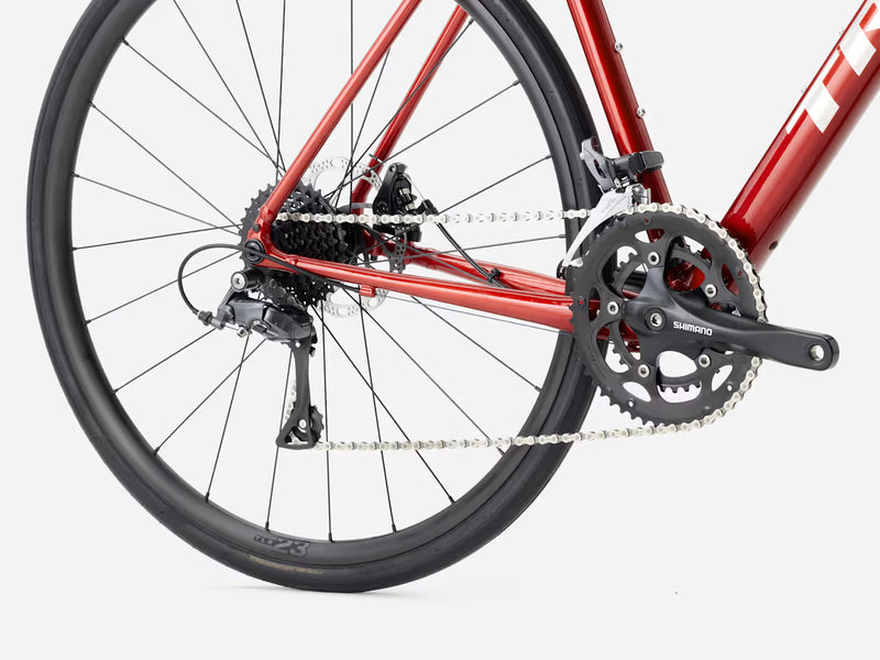 Close-up of a red endurance road bicycle's rear wheel and gear system on a white background
