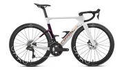 A high-end performance road bicycle with a white and dark purple carbon fiber frame, black drop handlebars, and black wheels, shown from a side profile on a white background.