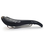 Product image of the Selle SMP Nymber Saddle in black leather with stitched SMP logo and central ergonomic cutout, diagonal view, where yuou can also see the product name 'nymber' in thast same stitching, side view.