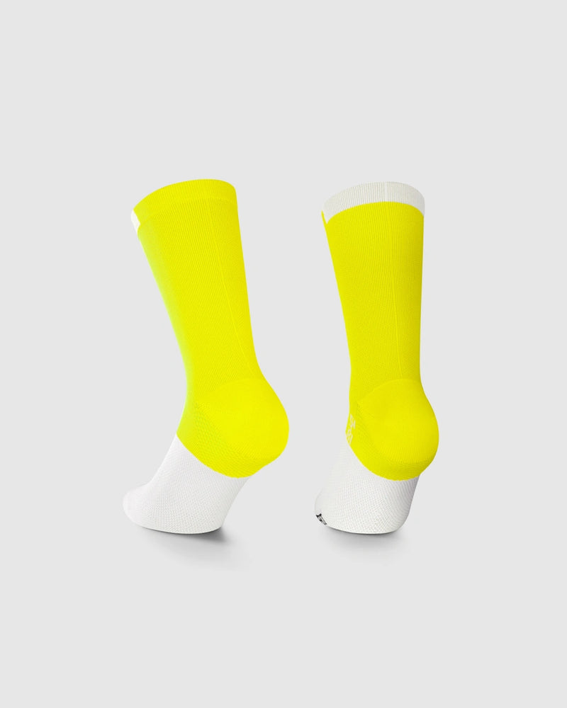Pair of yellow socks with white toes and heels on a light gray background