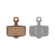 Two brake pads, one brown and one gray with text, on a white background