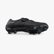 Angled dynamic view of black Shimano SH-XC503 shoe showing lower ULTREAD outsole tread lugs combined with the lateral BOA dial closure