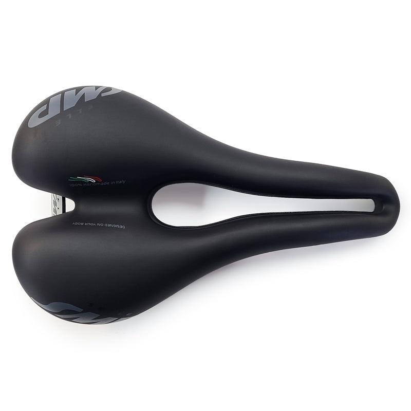 Selle SMP TRK Medium Saddle top view in black with white SMP logo on the rear, embossed “Designed On Your Body” and “Handmade in Italy” text in the ergonomic channel, and Italy‑colour thread detail, tip facing right.
